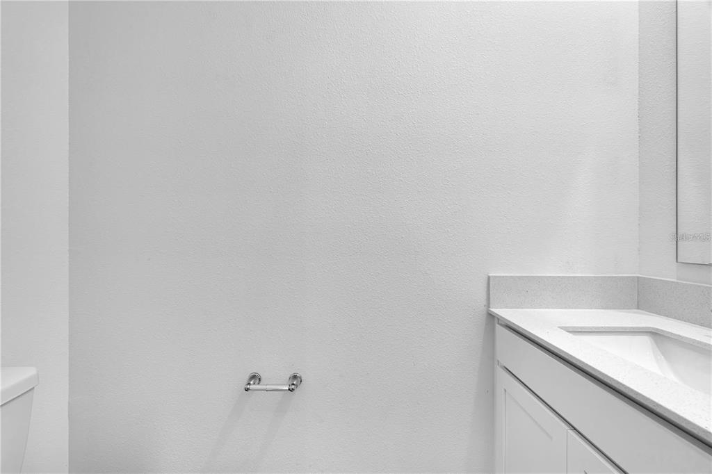 A bathroom features a white vanity with a countertop, a toilet, and a wall-mounted holder — 294 BOGEY DRIVE, DAVENPORT, FL