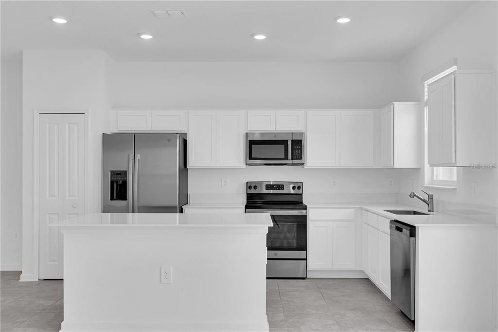 A modern kitchen features white cabinets, stainless steel appliances, and a central island — 294 BOGEY DRIVE, DAVENPORT, FL