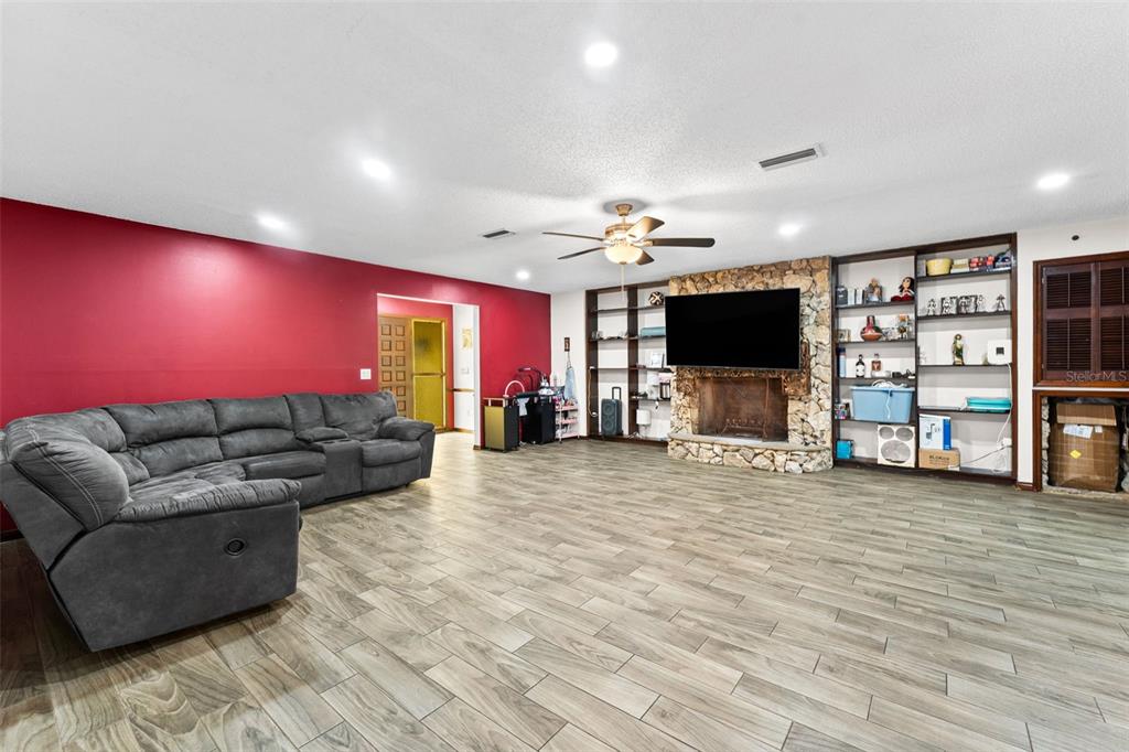 A living room features a red accent wall, gray sectional sofa, and stone fireplace — 3852 S LAKE ORLANDO PARKWAY, ORLANDO, FL