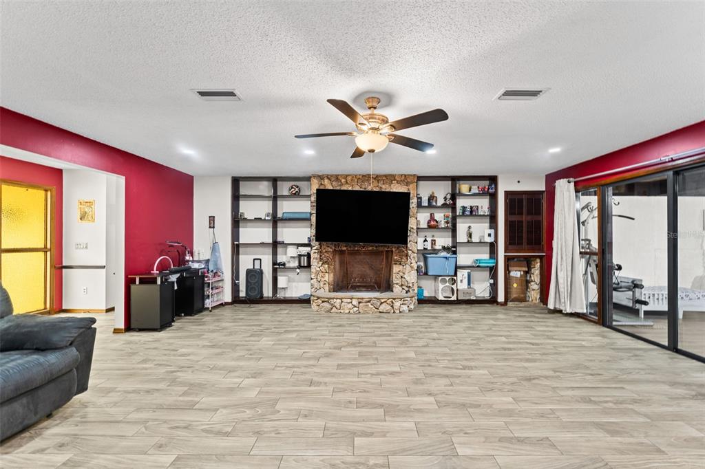A spacious living room features wood-look tile floors, a stone fireplace, and built-in shelving — 3852 S LAKE ORLANDO PARKWAY, ORLANDO, FL