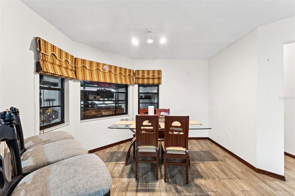A dining room features a glass-topped table, wooden chairs, and windows with bamboo shades — 3852 S LAKE ORLANDO PARKWAY, ORLANDO, FL