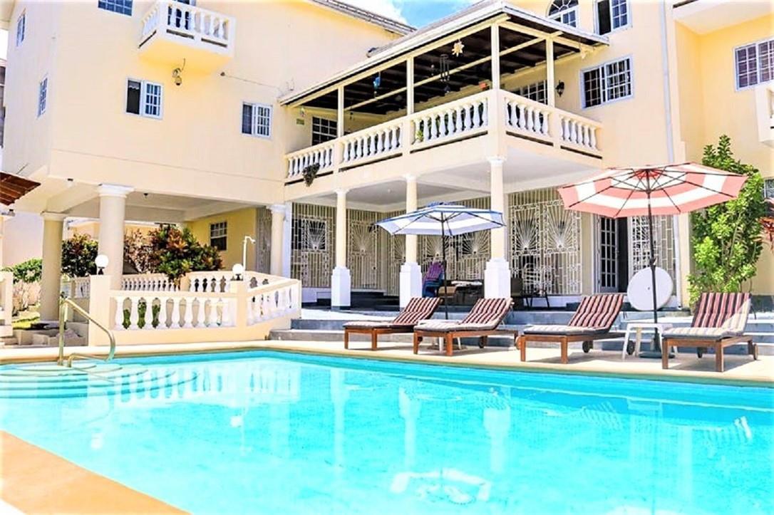 A multi-story yellow house with a swimming pool, lounge chairs, and umbrellas on the patio — 368 Hartsfield N Hartsfield Ironshore Drive, FL