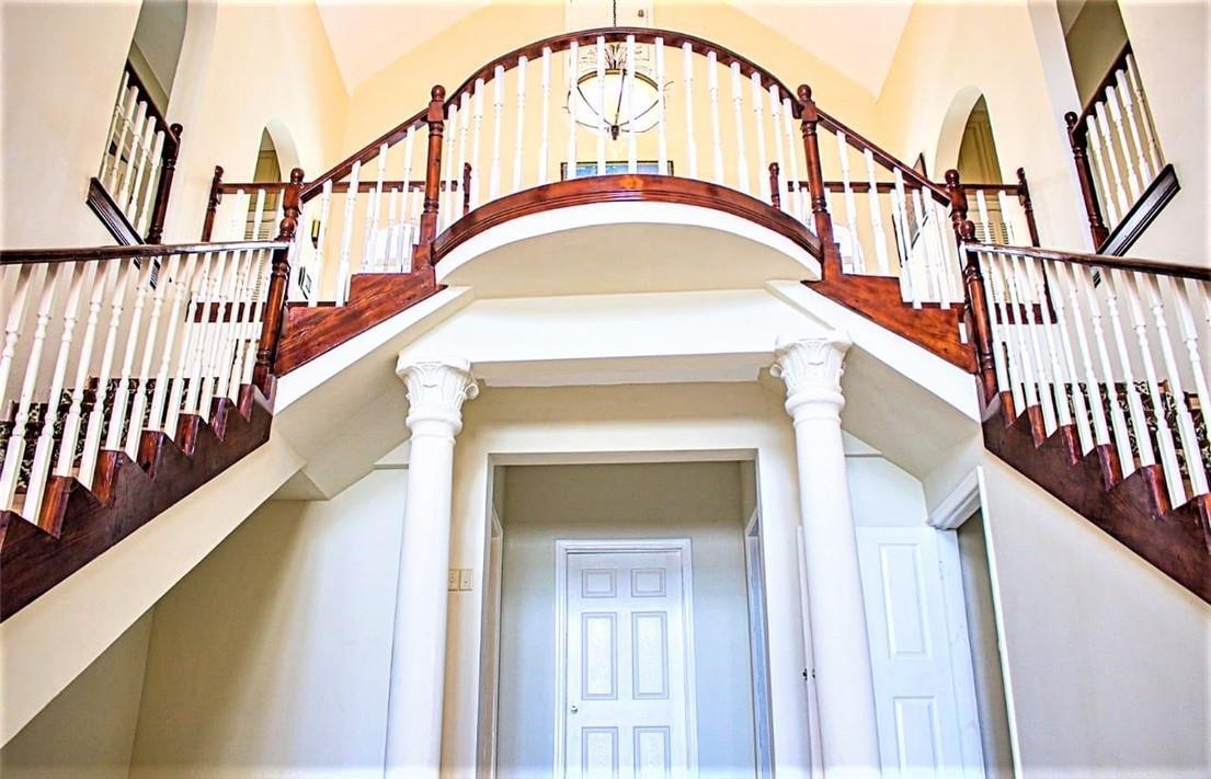 A grand foyer features a curved balcony, dual staircases with wooden railings, and white columns — 368 Hartsfield N Hartsfield Ironshore Drive, FL