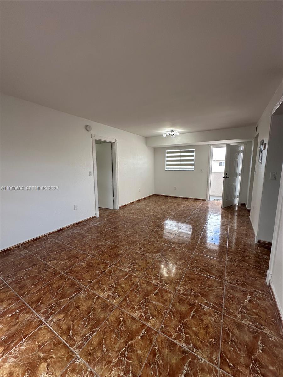 An empty room features brown marble-patterned tile flooring, white walls, and an open doorway — 6091 W 22nd Ct # 408, Hialeah FL 33016, HIALEAH, FL