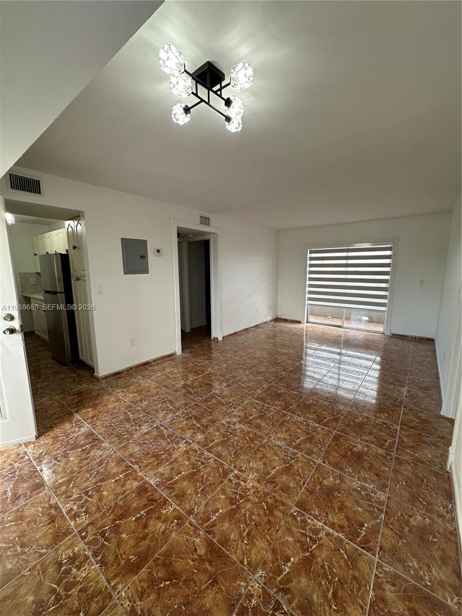 An empty living room features brown marble-style tile flooring and a modern geometric ceiling light — 6091 W 22nd Ct # 408, Hialeah FL 33016, HIALEAH, FL