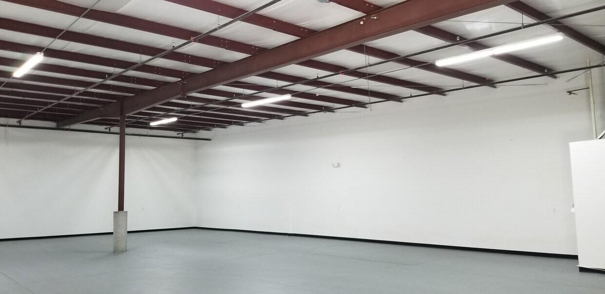 An empty warehouse space features white walls, a gray floor, and exposed steel ceiling beams — 6555 Garden Road, Riviera Beach FL 33404, RIVIERA BEACH, FL