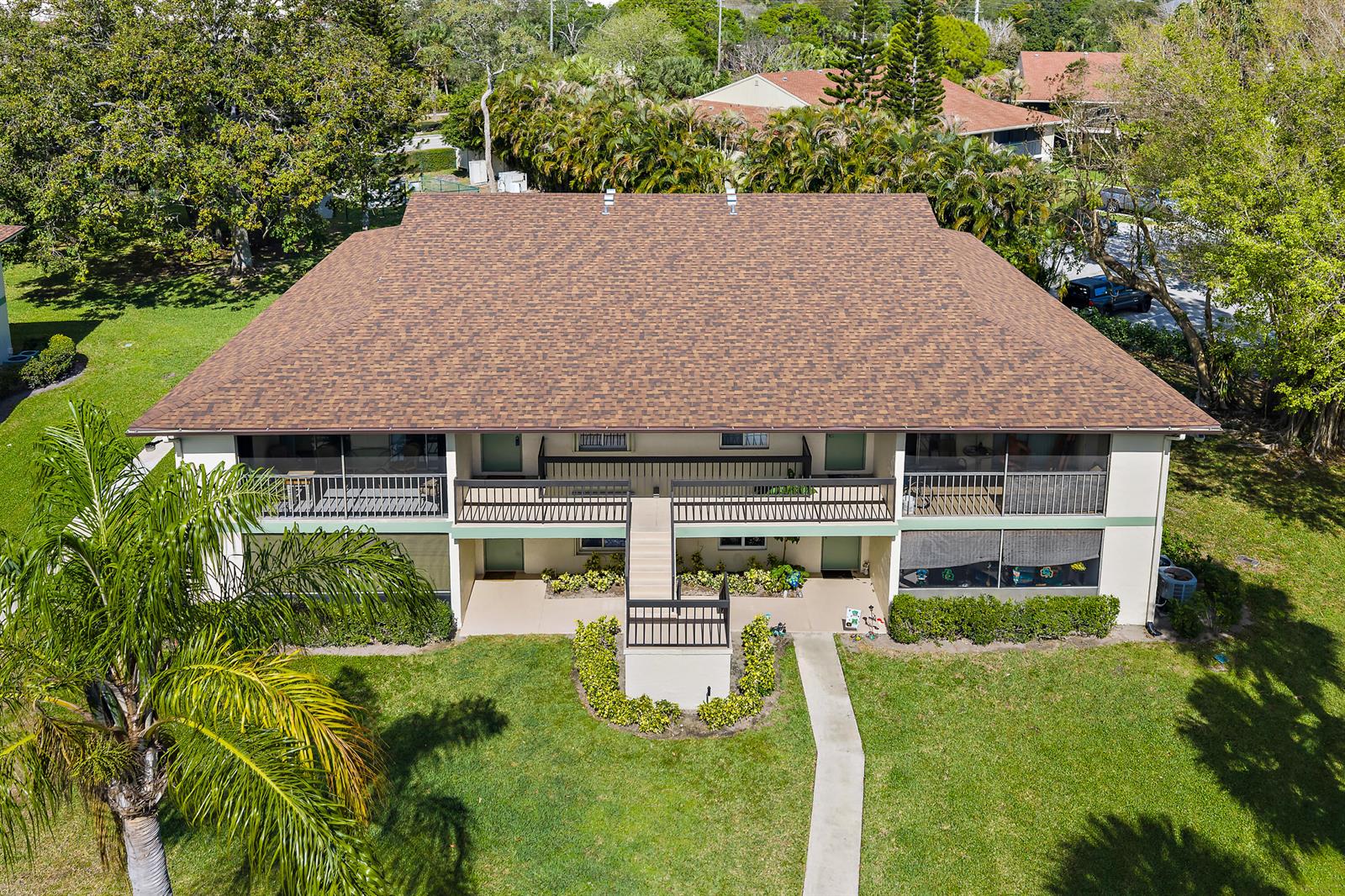An aerial view of a two-story apartment building with a brown shingled roof — 6426 Chasewood Drive, Jupiter FL 33458, JUPITER, FL