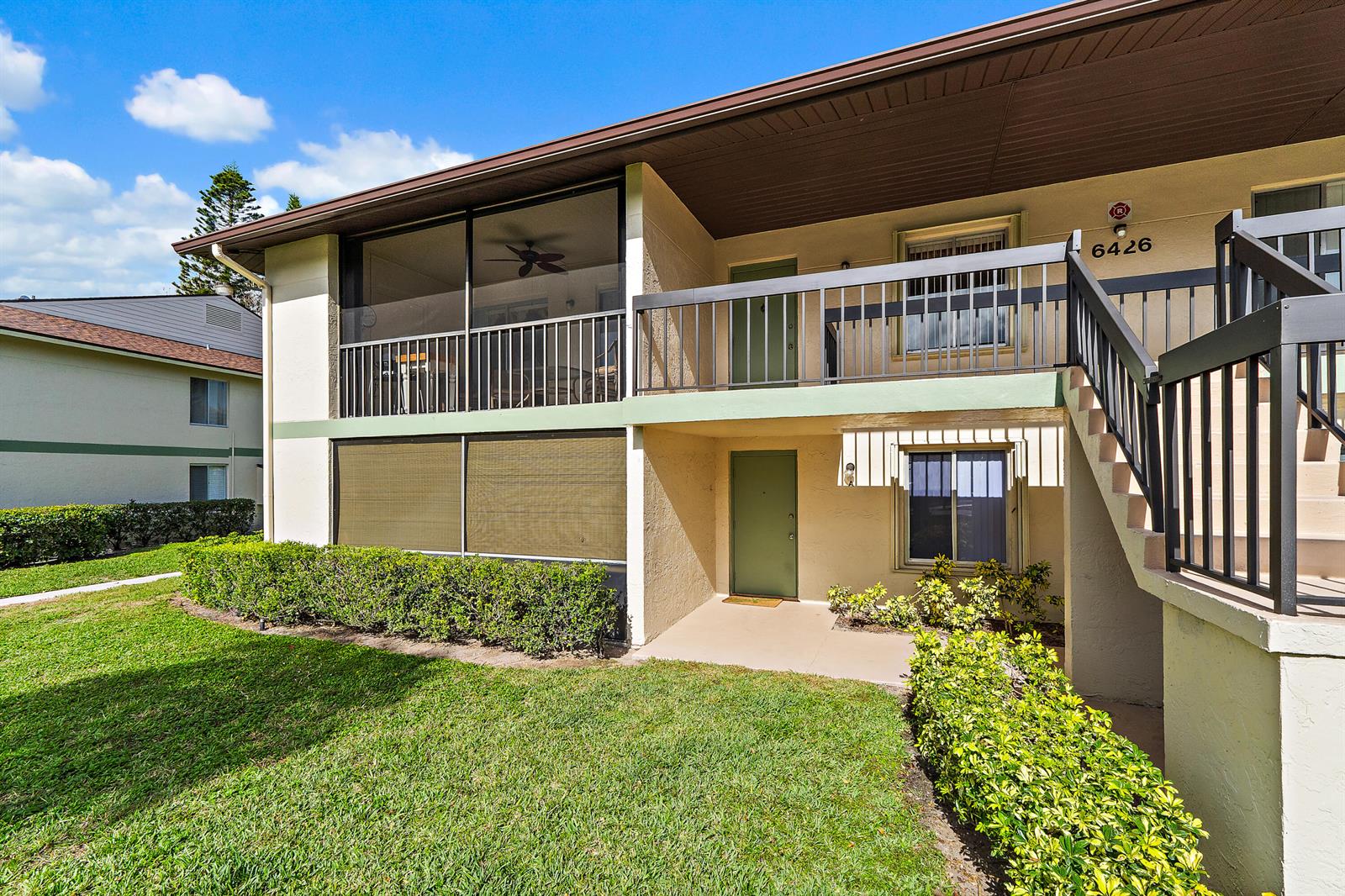A two-story apartment building exterior features a screened balcony, green doors, and outdoor stairs — 6426 Chasewood Drive, Jupiter FL 33458, JUPITER, FL