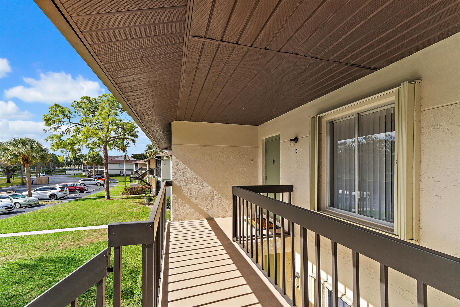 An outdoor apartment balcony with a brown railing and ceiling overlooking a parking lot — 6426 Chasewood Drive, Jupiter FL 33458, JUPITER, FL