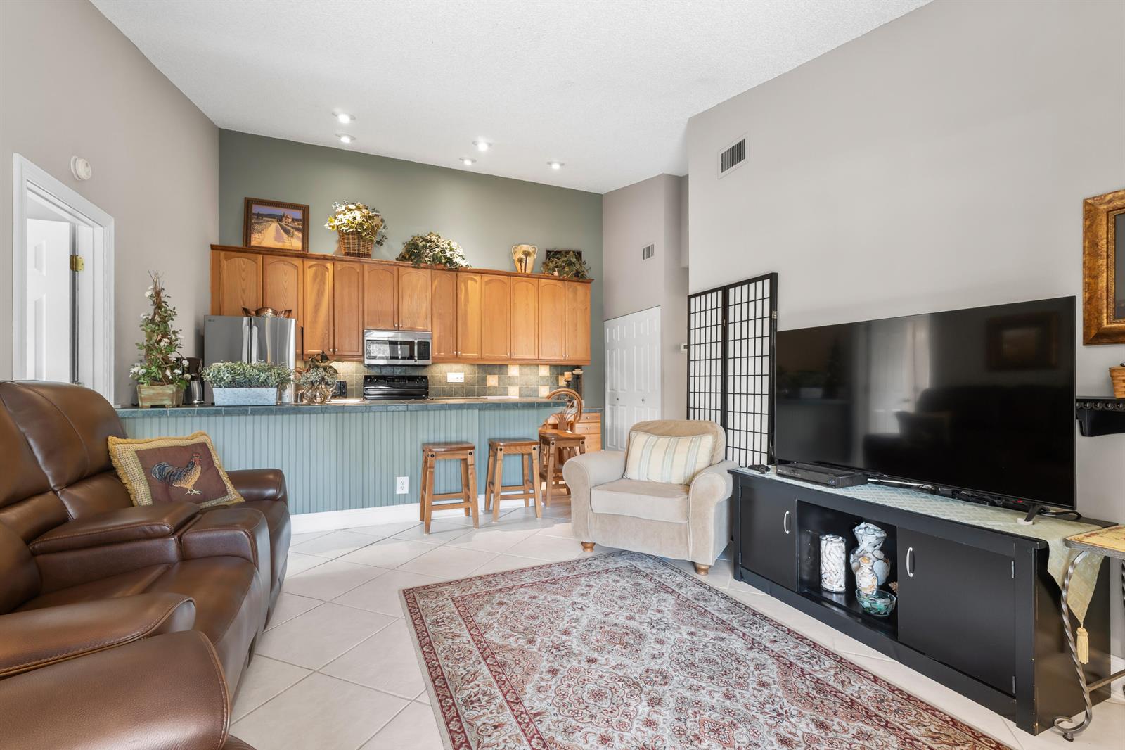 A living room with a brown leather recliner, a television console, and an open kitchen — 6426 Chasewood Drive, Jupiter FL 33458, JUPITER, FL