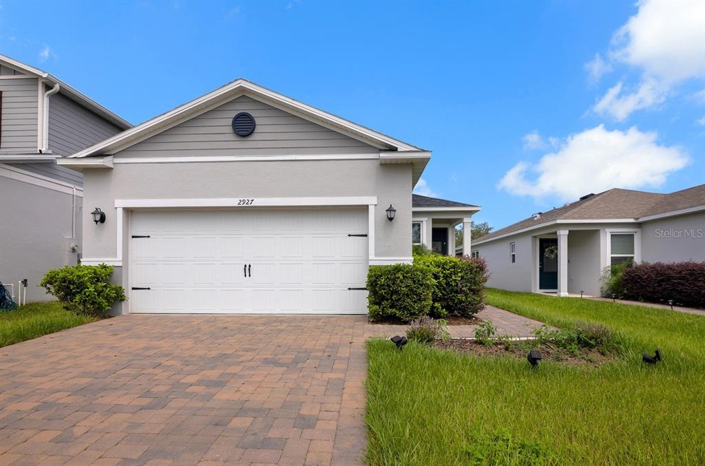 A single-story house with a paved driveway, two-car garage, and a small front yard — 2927 SANCTUARY DRIVE, CLERMONT, FL
