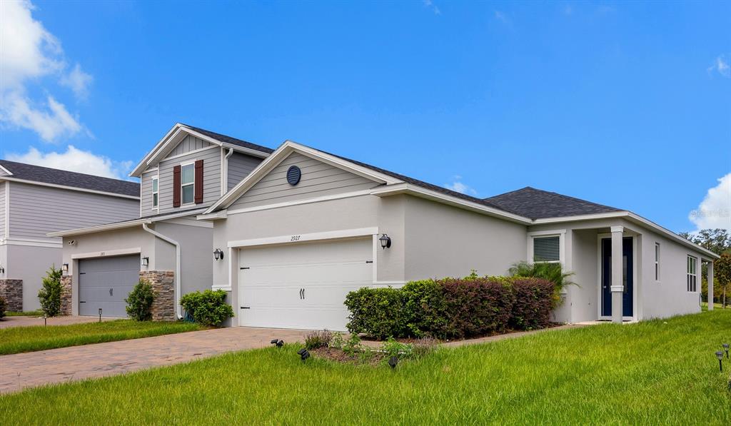 A single-story gray house with a two-car garage and a landscaped front yard — 2927 SANCTUARY DRIVE, CLERMONT, FL