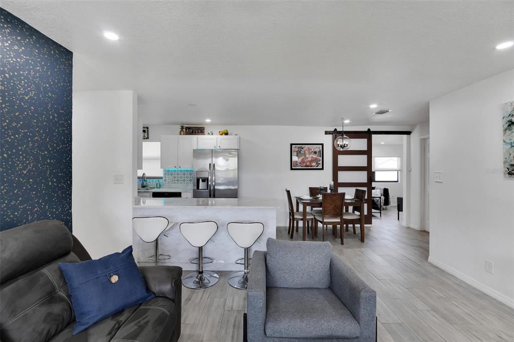 An open-concept living area features a kitchen with a marble island, bar stools, and dining space — 4731 W MONTGOMERY AVENUE, TAMPA, FL