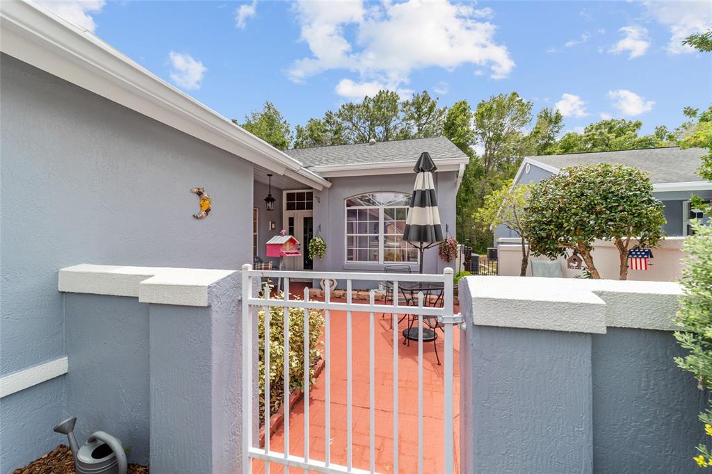 A gated courtyard with a red brick patio leads to the entrance of a house — 11460 SW 78TH CIRCLE, OCALA, FL