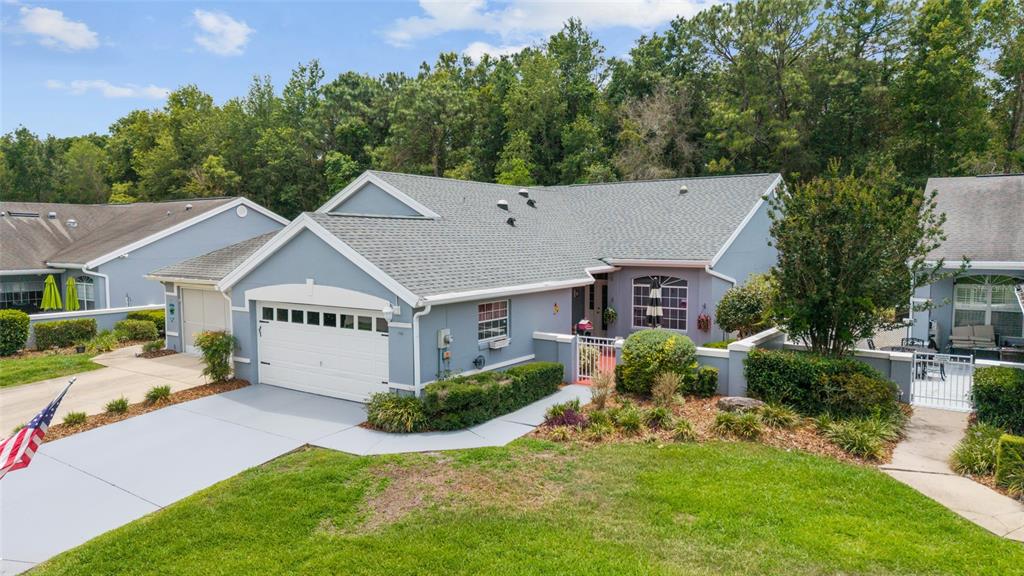 An exterior view of a blue single-story house with a white garage and front courtyard — 11460 SW 78TH CIRCLE, OCALA, FL