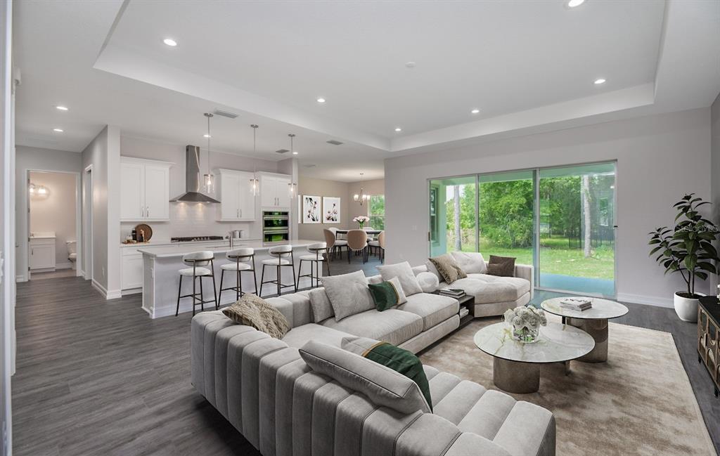 An open-concept living room and kitchen featuring white cabinetry, a large sectional, and sliding doors — 8314 NW 17TH CIRCLE, OCALA, FL