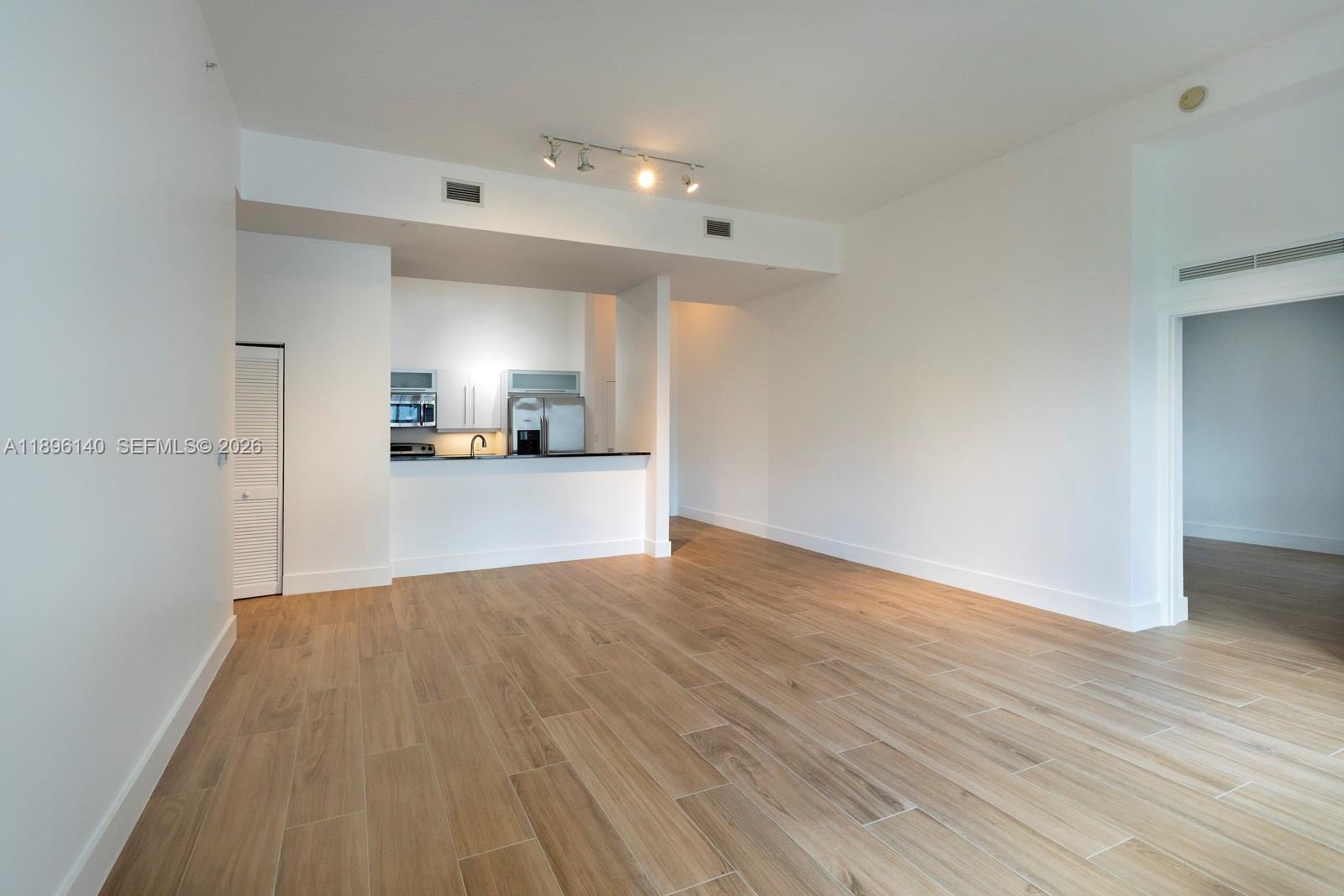 An open-concept living area features light wood-look tile flooring and a kitchen with white cabinetry — 7350 SW 89th St # 514S, Miami FL 33156, MIAMI, FL