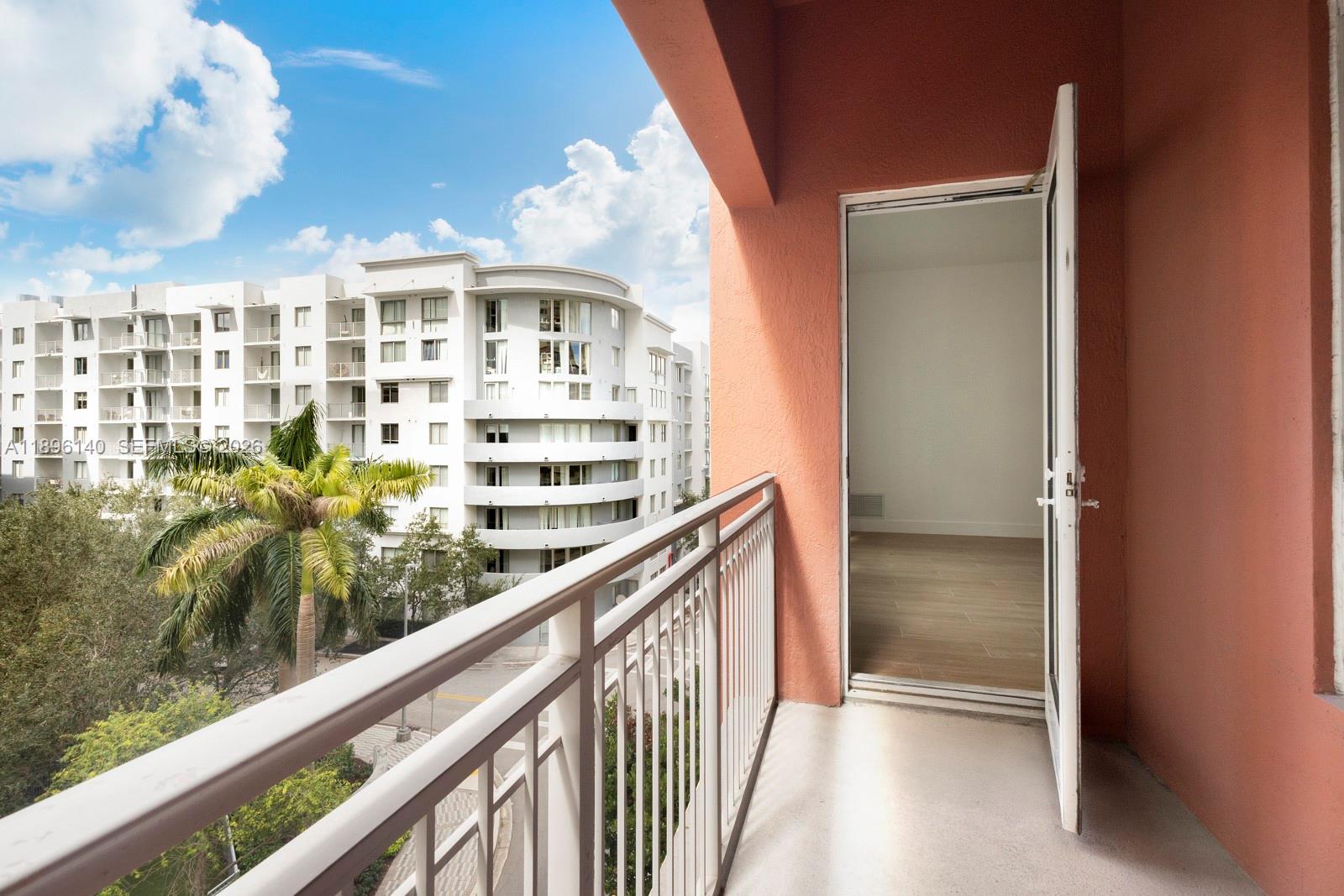 A balcony with a metal railing overlooks a street and a modern white apartment building — 7350 SW 89th St # 514S, Miami FL 33156, MIAMI, FL