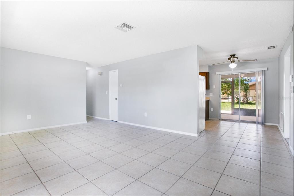 A living room with light gray walls, white tile flooring, and a sliding glass door — 405 LONG DRIVE, POINCIANA, FL