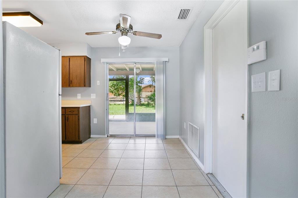 A kitchen and dining area with tile floors, wooden cabinets, and a sliding glass door — 405 LONG DRIVE, POINCIANA, FL