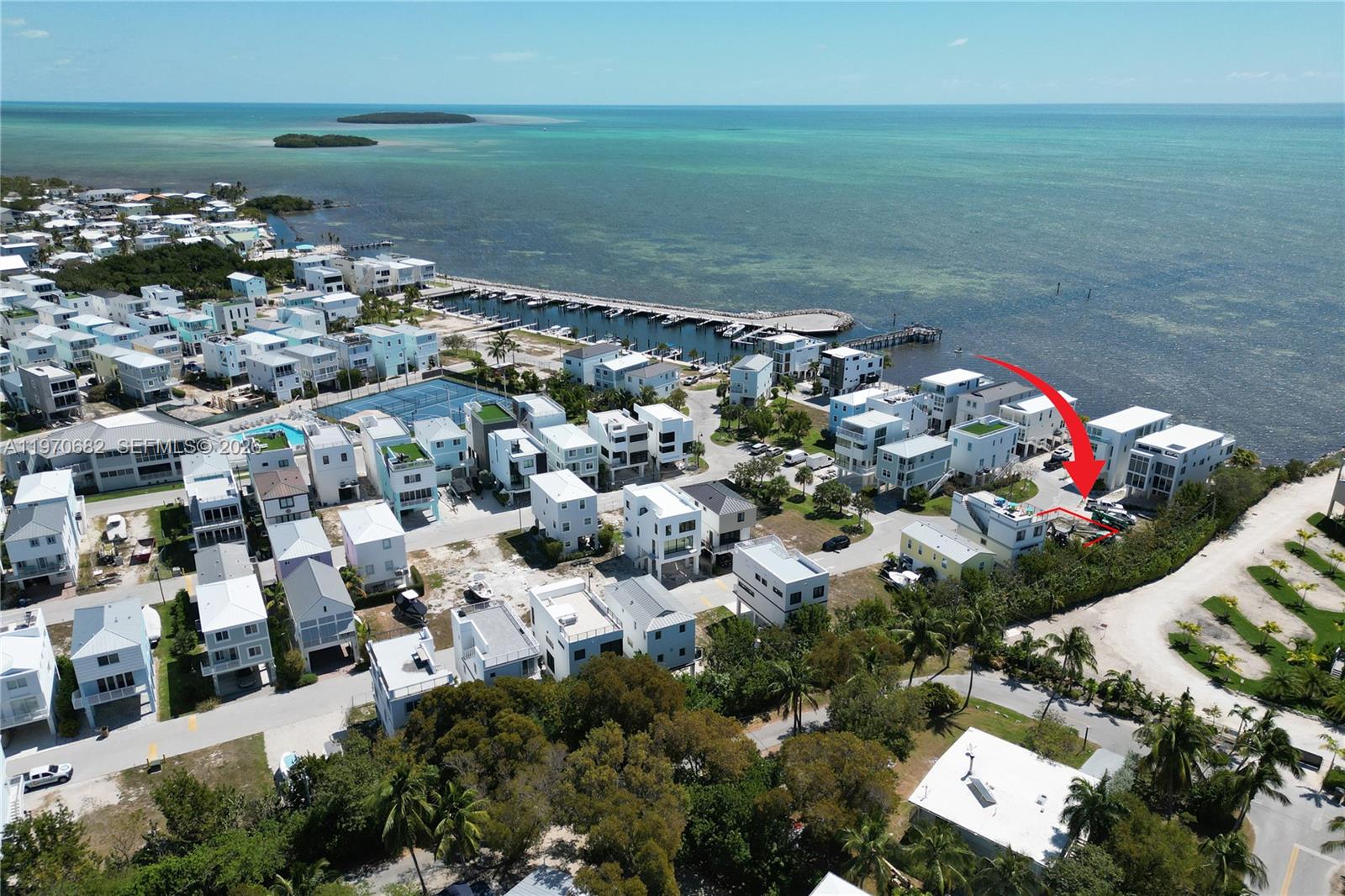 An aerial view shows a coastal neighborhood with modern houses and a boat dock — 94825 Overseas Hwy, Key Largo FL 33037, KEY LARGO, FL
