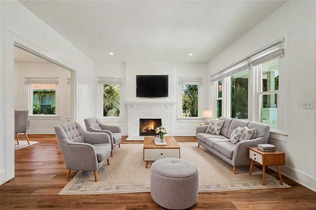 A bright living room features a white brick fireplace, gray furniture, and hardwood floors — 2527 HIGHLAND STREET S, ST PETERSBURG, FL