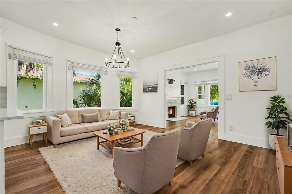 A bright living room features a beige sofa, two armchairs, a fireplace, and hardwood floors — 2527 HIGHLAND STREET S, ST PETERSBURG, FL