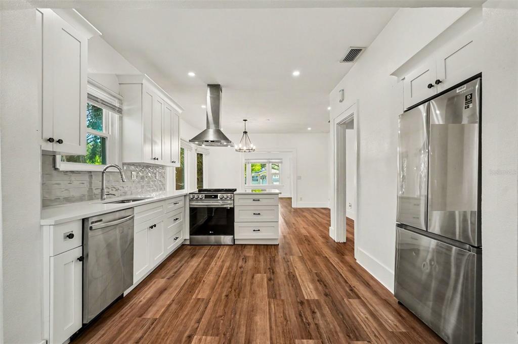 A modern kitchen features white cabinetry, stainless steel appliances, and wood-look flooring — 2527 HIGHLAND STREET S, ST PETERSBURG, FL