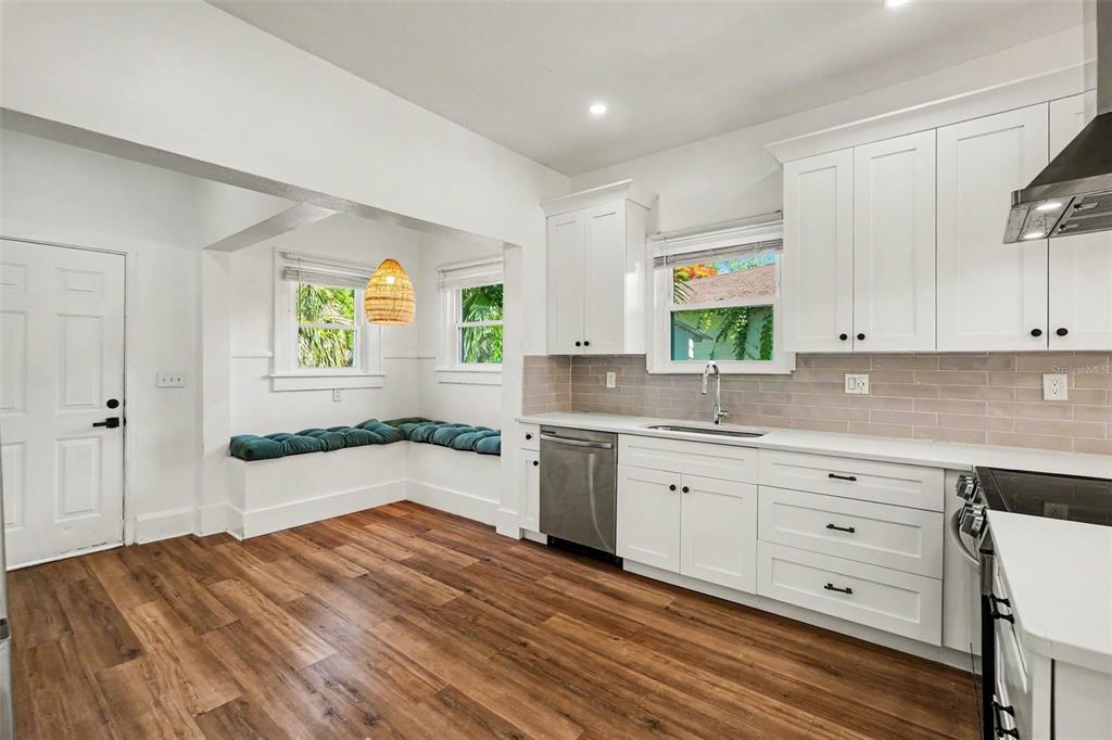 A kitchen with white cabinets, stainless steel appliances, a tile backsplash, and a built-in bench — 2527 HIGHLAND STREET S, ST PETERSBURG, FL