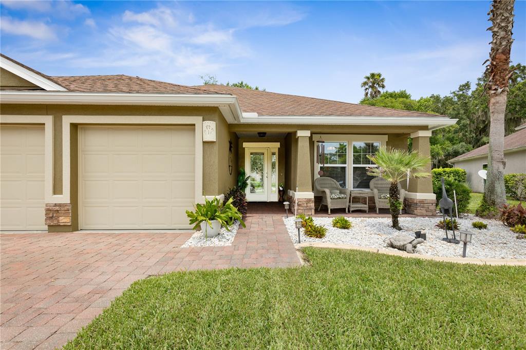 A beige house exterior features a paved walkway, a garage, and a covered front porch — 41 AUBERRY DRIVE, PALM COAST, FL