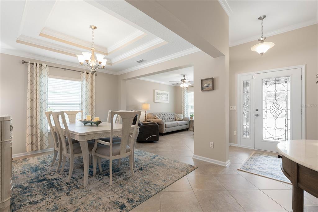 A dining area with a tray ceiling and chandelier opens into a living room — 41 AUBERRY DRIVE, PALM COAST, FL