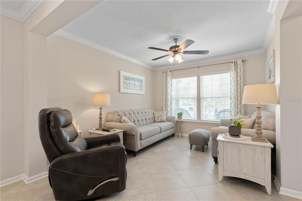 A living room features a leather recliner, a tufted sofa, tile floors, and a ceiling fan — 41 AUBERRY DRIVE, PALM COAST, FL
