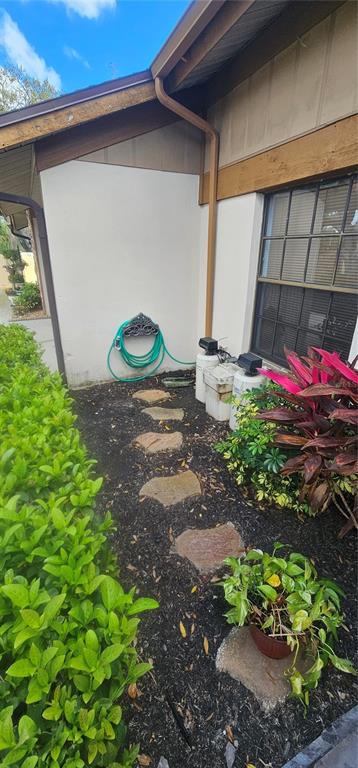 A side yard features a stone path, a hose, and water treatment equipment against the house — 4075 SHORESIDE CIRCLE, TAMPA, FL