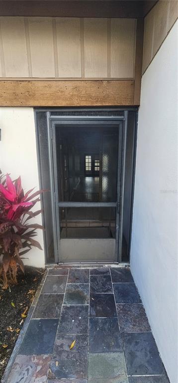 A front entryway features a dark metal screen door, slate tile flooring, and a wooden beam — 4075 SHORESIDE CIRCLE, TAMPA, FL