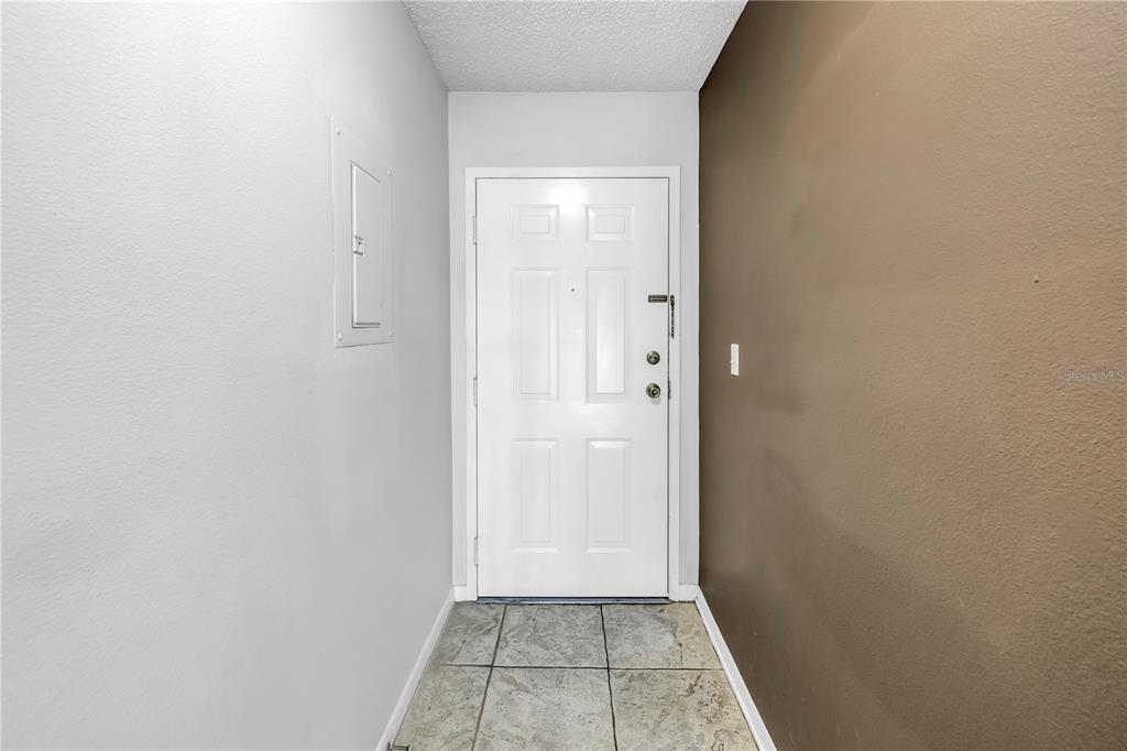 An entryway features a white door, tiled floor, and walls painted in gray and brown — 650 ISLAND WAY UNIT 204, CLEARWATER BEACH, FL
