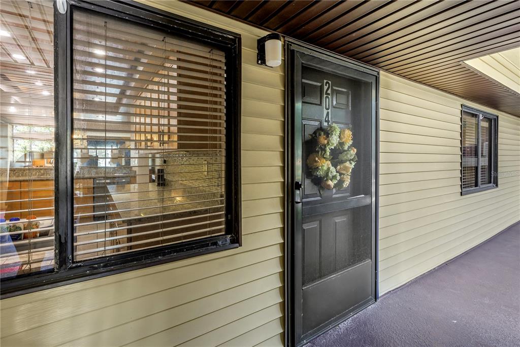 A view of a building exterior featuring a front door, a window, and siding — 650 ISLAND WAY UNIT 204, CLEARWATER BEACH, FL