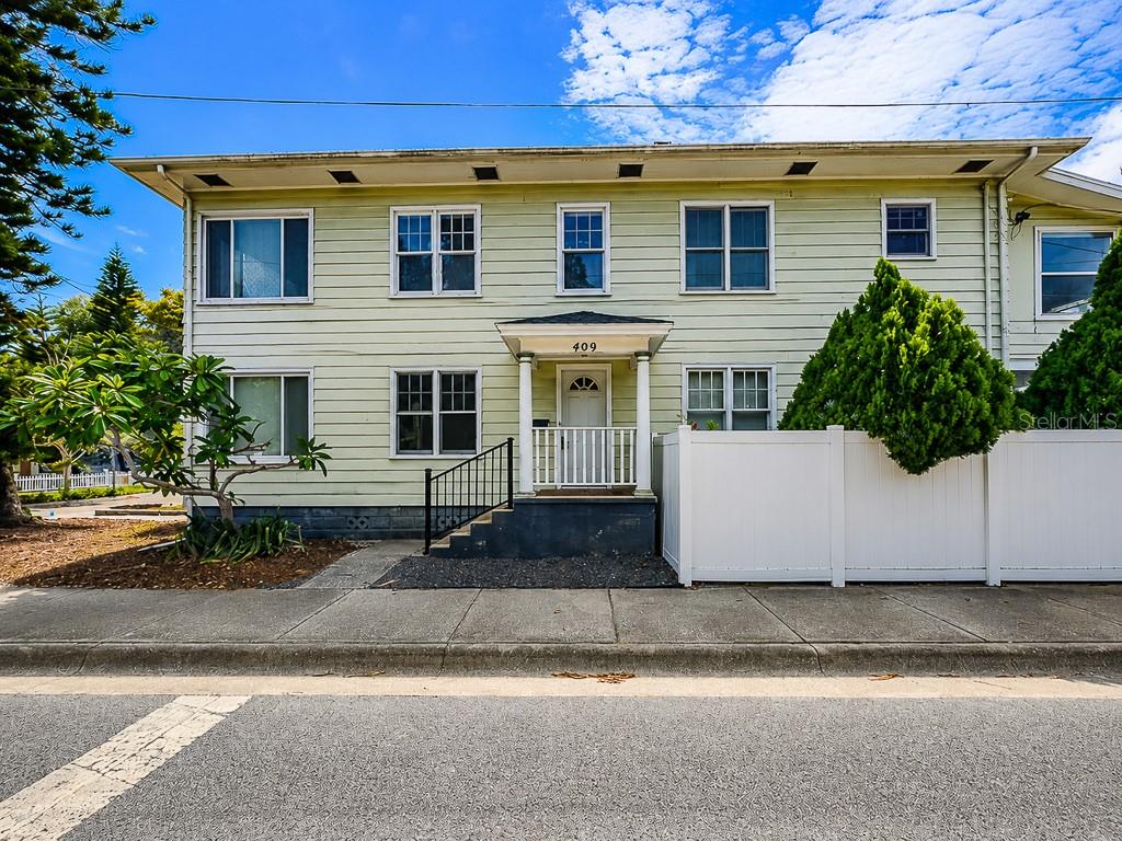 A two-story, light green house with a front porch and a white privacy fence — 400 20TH STREET N, ST PETERSBURG, FL