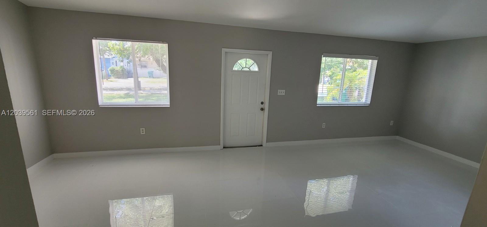 A room with gray walls, white tile flooring, two windows, and a central white door — 10250 SW 173rd Ter, Miami FL 33157, MIAMI, FL