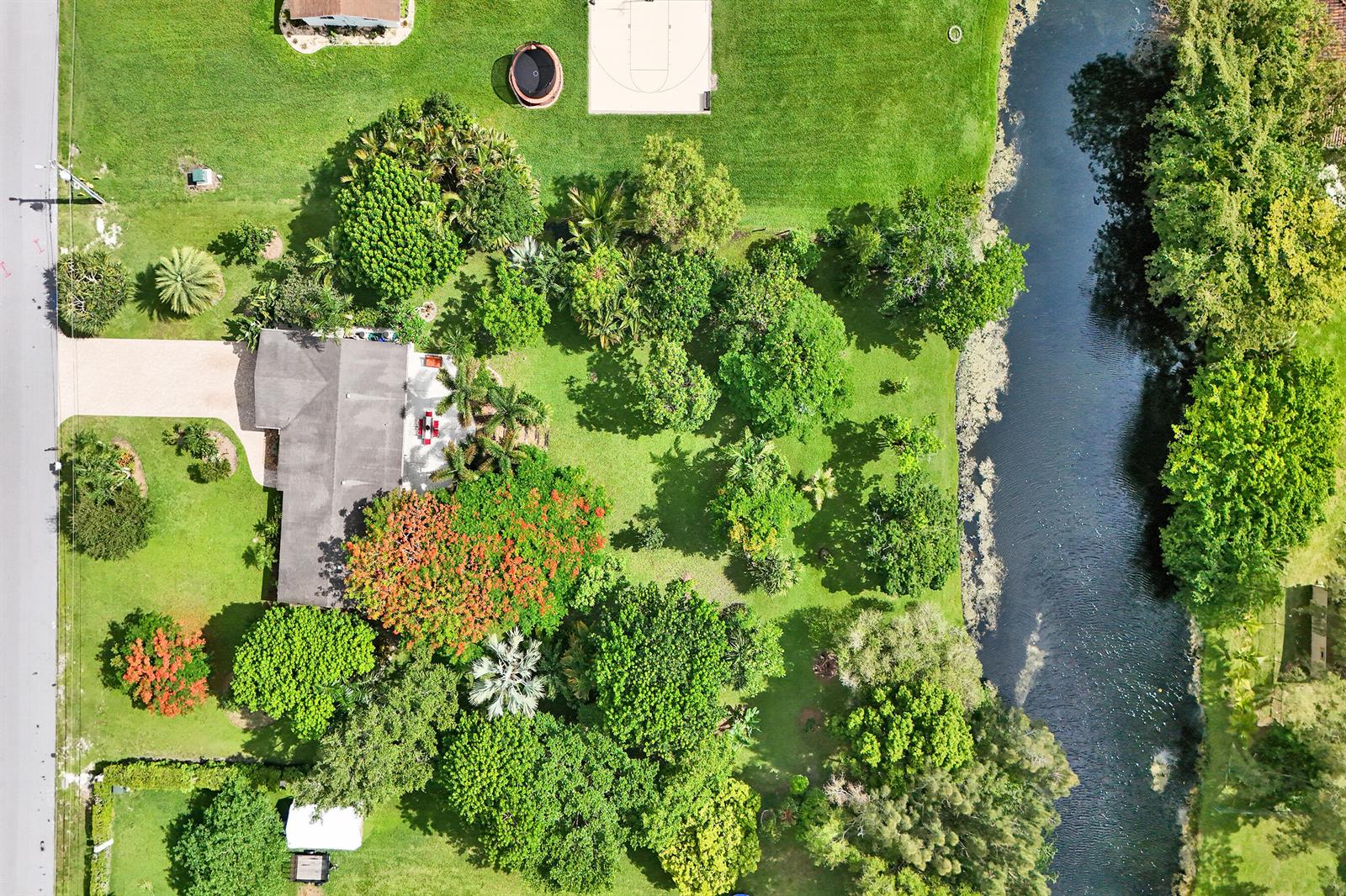 An aerial view shows a house with a large yard, trees, and a canal — 3951 SW 137th Avenue, Miramar FL 33027, MIRAMAR, FL
