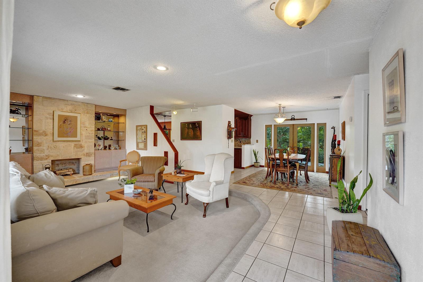 A living room with a stone fireplace, carpeted seating area, and adjacent dining room — 3951 SW 137th Avenue, Miramar FL 33027, MIRAMAR, FL