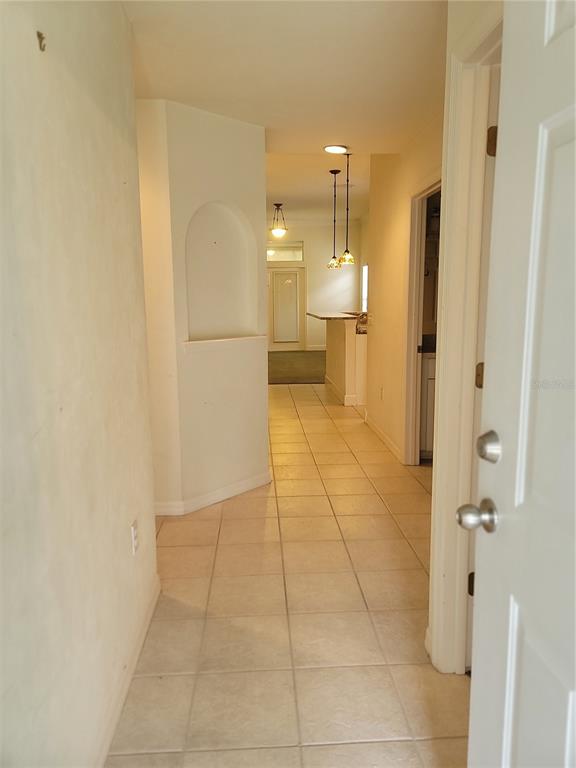 A tiled hallway leads past an arched wall niche toward a kitchen with hanging lights — 6312 NW 109TH PLACE, ALACHUA, FL