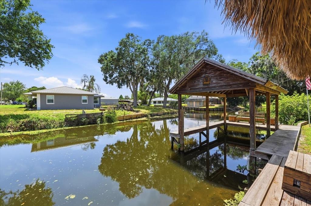 A wooden boat dock sits on a canal in front of a gray house — 2770 LAKE PIERCE DRIVE, LAKE WALES, FL