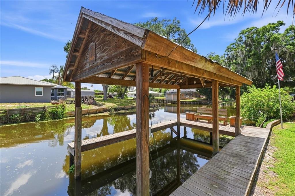 A wooden boat dock with a covered slip sits over a canal near a house — 2770 LAKE PIERCE DRIVE, LAKE WALES, FL