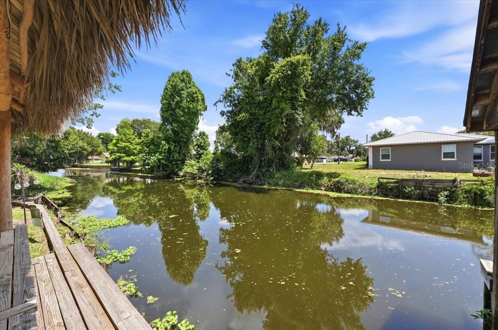 A wooden deck overlooks a narrow canal lined with trees and a nearby house — 2770 LAKE PIERCE DRIVE, LAKE WALES, FL