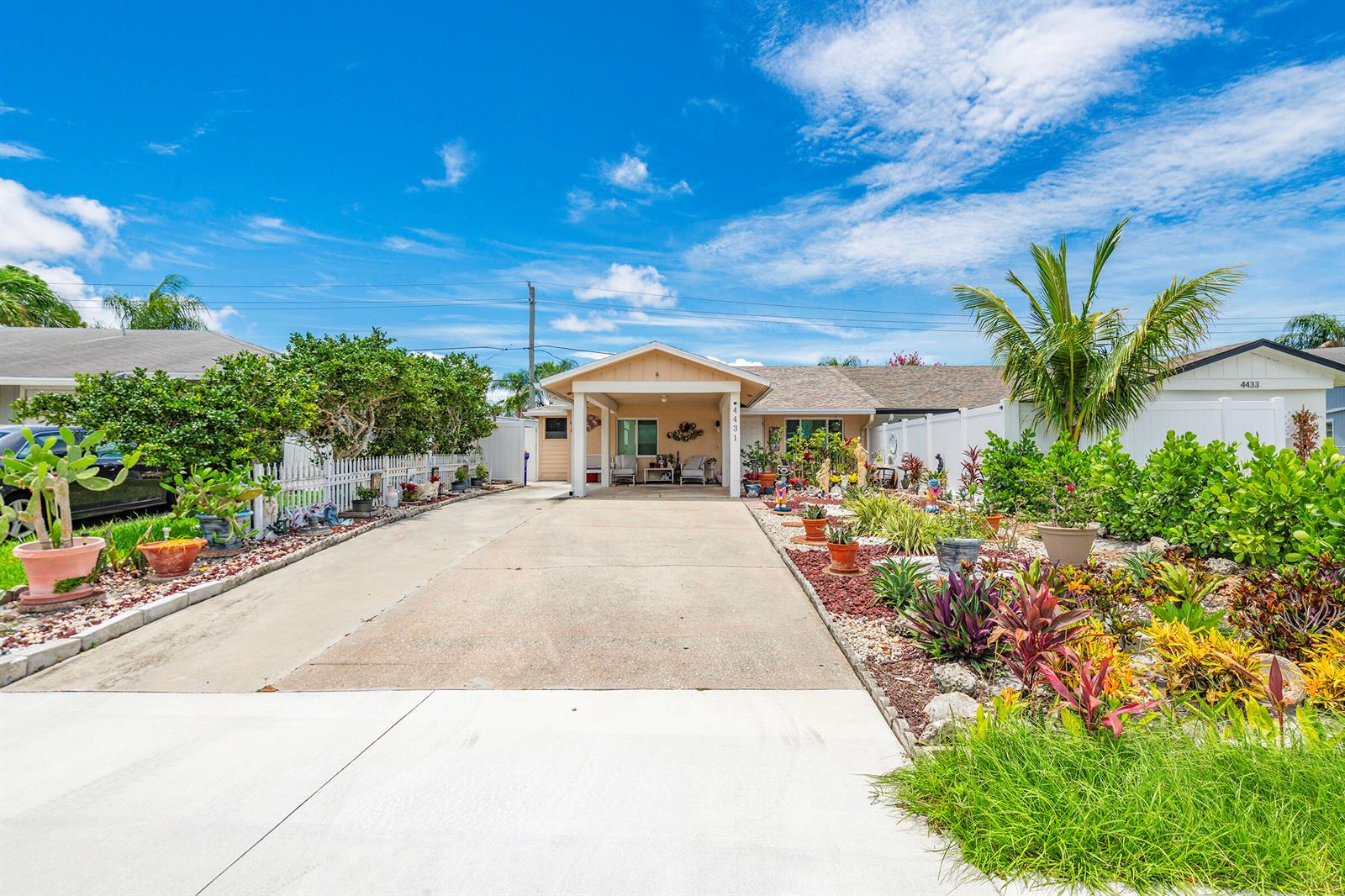 A single-story house with a concrete driveway, a covered entryway, and extensive front yard landscaping — 4431 SE Village Road, Stuart FL 34997, STUART, FL