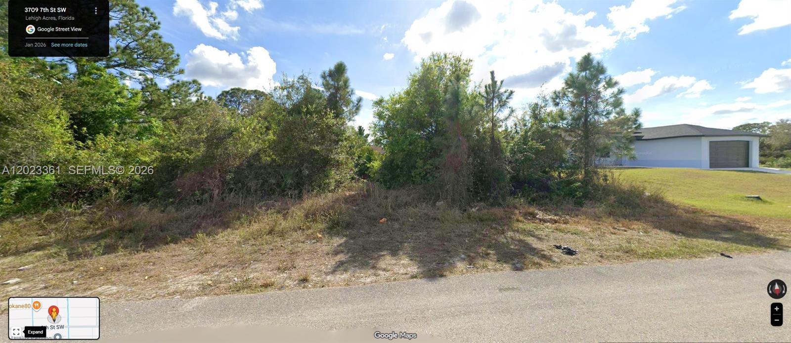 A vacant, overgrown residential lot with trees and shrubs next to a single-family home — 3709 7th ST SW, Lehigh Acres FL 33976, LEHIGH ACRES, FL