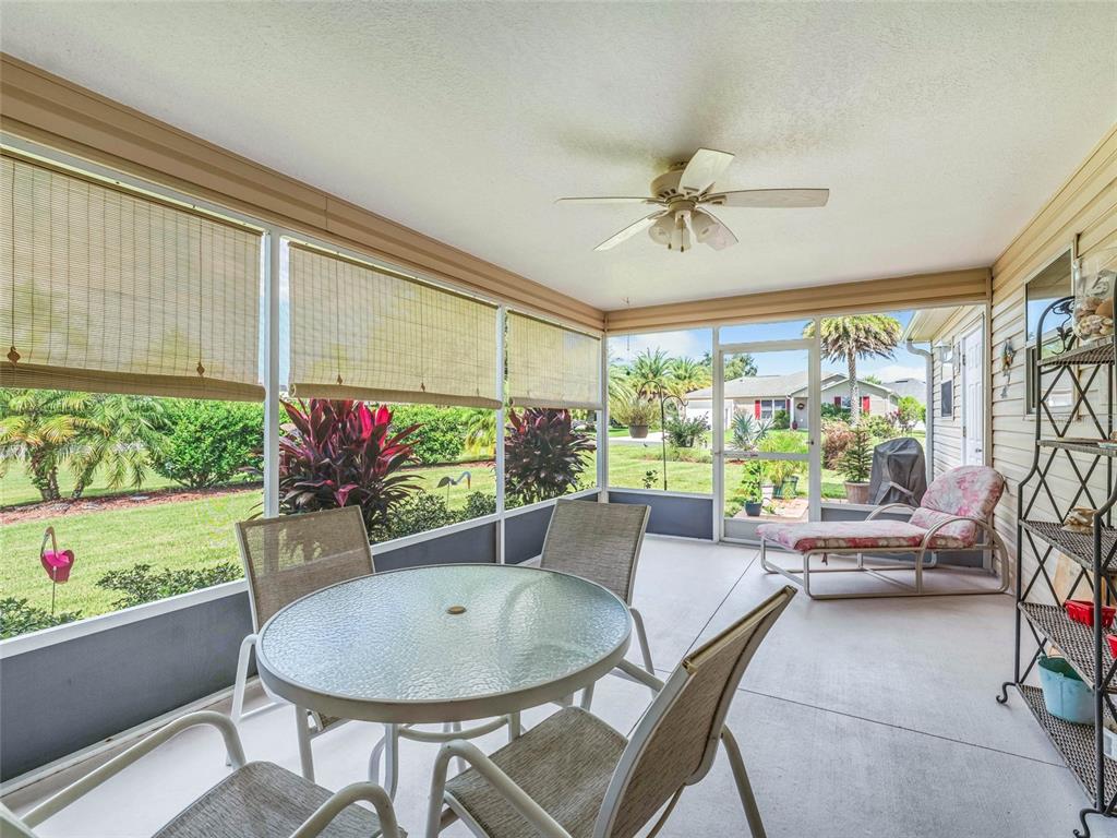 A screened-in patio features a glass-topped dining set, a lounge chair, and outdoor views — 1704 LISETTE WAY, THE VILLAGES, FL
