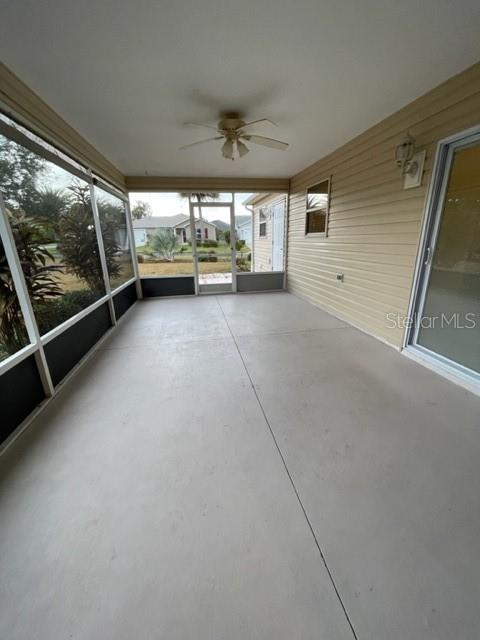 A screened-in patio features a ceiling fan, light-colored concrete flooring, and sliding glass doors — 1704 LISETTE WAY, THE VILLAGES, FL