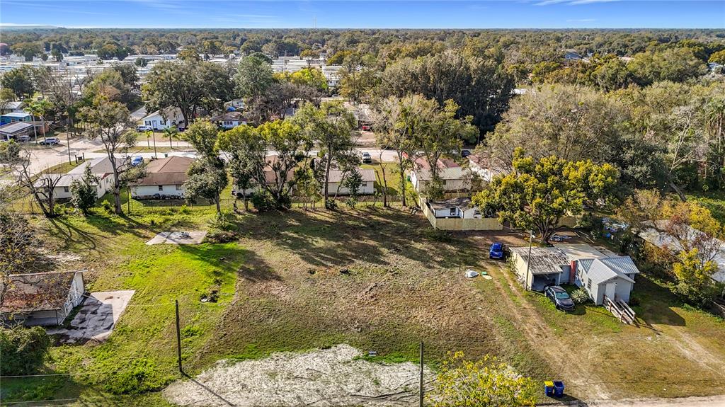 An aerial view shows a large, grassy vacant lot surrounded by residential houses and trees — 38548 CALUMET AVENUE, ZEPHYRHILLS, FL