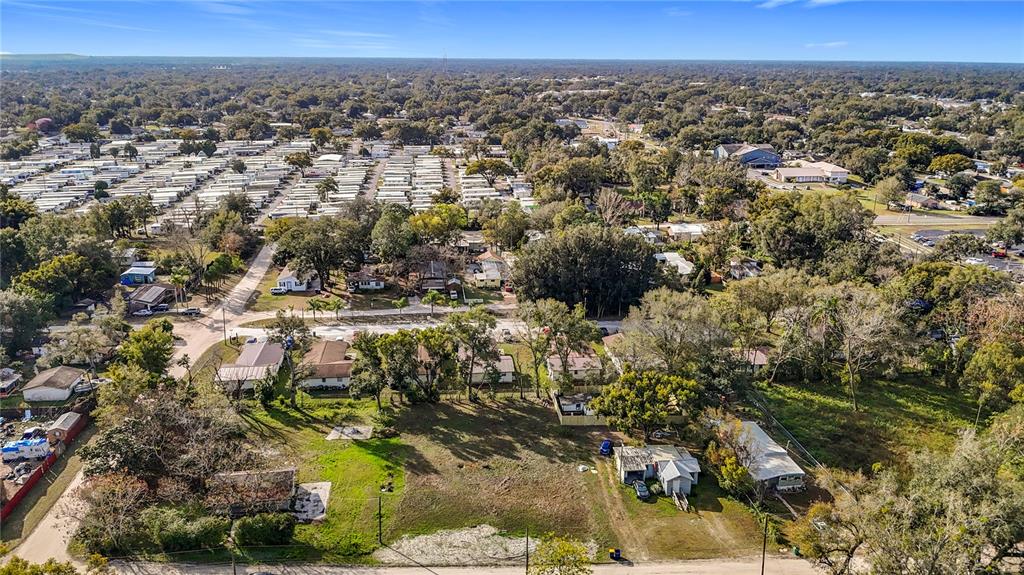 An aerial view shows a residential area with a large vacant lot and mobile homes — 38548 CALUMET AVENUE, ZEPHYRHILLS, FL